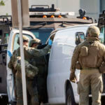 Members of a SWAT team enter a van and look through its contents in Torrance Calif., Sunday, Jan. 22,