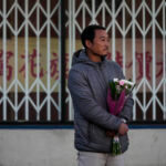 Hunter Zhao, 41, holds flowers to honor the victims killed in Saturday's ballroom dance studio shooting