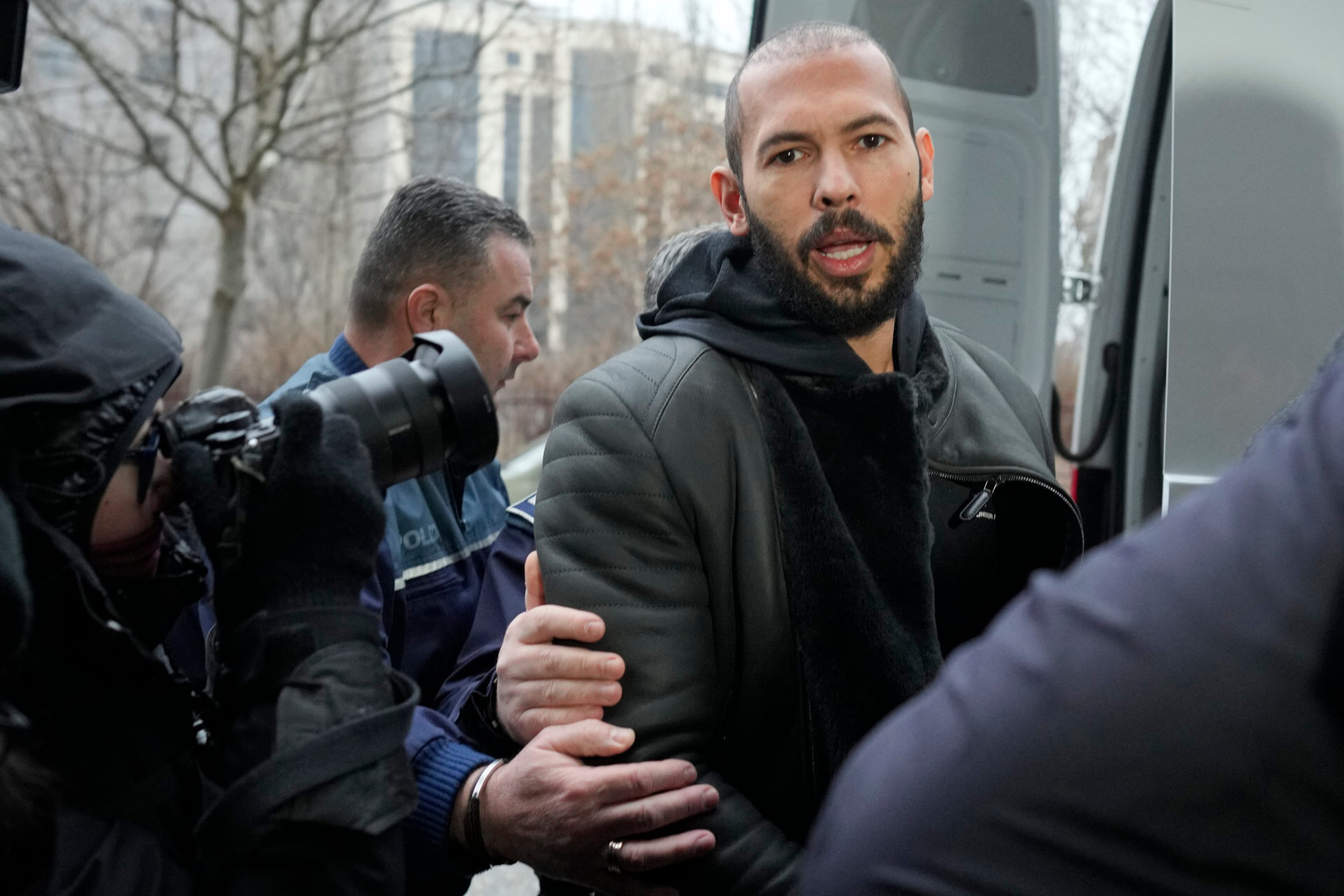 Police officers escort Andrew Tate, handcuffed to his brother Tristan