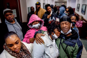 Latryna Sims, partner of Calvin Munerlyn, center, cries on the shoulder of his uncle