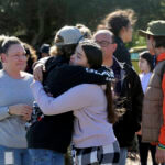 Cameron Gonzalez, 15, hugs fellow student Izzy Sullivan 18, while Cameron's mom, Amy Gonzalez, stands nearby after students were released from the football field following a fatal stabbing at Montgomery High School.