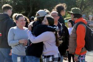 Cameron Gonzalez, 15, hugs fellow student Izzy Sullivan 18, while Cameron's mom, Amy Gonzalez, stands nearby after students were released from the football field following a fatal stabbing at Montgomery High School.