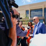 Attorney Bjorn Brunvand stands with reporters and photographers outside of a courthouse