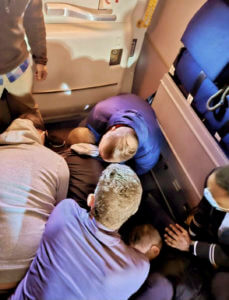 Passengers and crew restrain a man who tried to open a plane's emergency door and tried to stab a flight attendant.