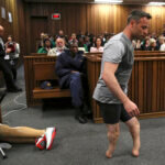 Oscar Pistorius' prosthetics lay on the floor as he walks on his amputated legs