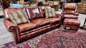 Photo of brown leather sofa with striped throw pillows, matching arm chair and ottoman