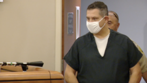 Dr. Carlos Chacon enters a courtroom, wearing a mask.