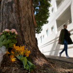 Woman walks past makeshift memorial at a tree