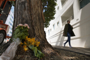 Woman walks past makeshift memorial at a tree