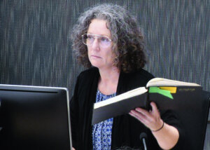 Kathleen Folbigg holds one of her diaries while appearing via video link