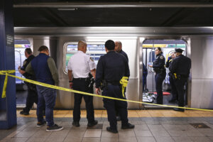 Police and crime scene tape outside of a subway car at a NYC subway station.