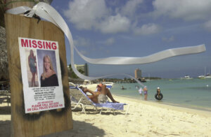 Missing person poster for Natalee Holloway on a pole with beach in background