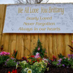 Banner and flowers comprise a memorial outside of a home