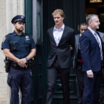 Daniel Penny, center, is walked by New York Police Department detectives