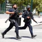 Armed police run across a street