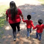 Veronica Pineda, left, walks down the driveway with her twin sons