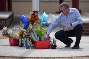 Principal Pete Armstrong adjusts flowers at a memorial