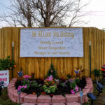 Banner and flowers serve as a memorial outside of a home