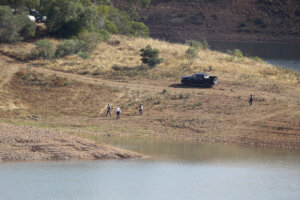 police search team walk on the shore of the Arade dam near Silves,