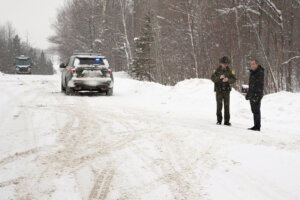 A Vermont state trooper talks to a man standing in the snow.