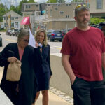 Denise Lodge, left, covers her face with a printout of the indictment against her