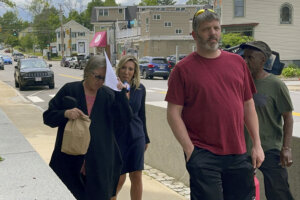 Denise Lodge, left, covers her face with a printout of the indictment against her