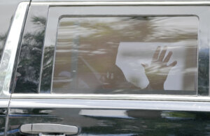 Donald Trump is seen waving from the back of a car.