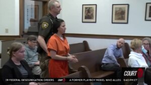 Taylor Schabusiness, in shackles and an orange jumpsuit, walks through the courtroom