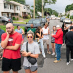 Residents try to take a look as police officers search the house where a suspect has been taken into custody on New York's Long Island