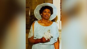 Photo of woman in a white dress and hat holding flowers