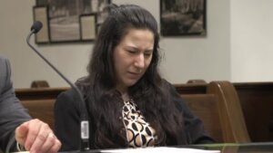 Woman sits looking down at a table in court