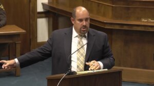 Man in a suit speaks at a lectern in court