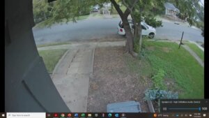 a tree and yard are seen from doorbell camera