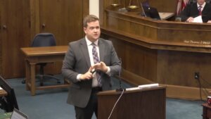 Man in suit stands at podium in court