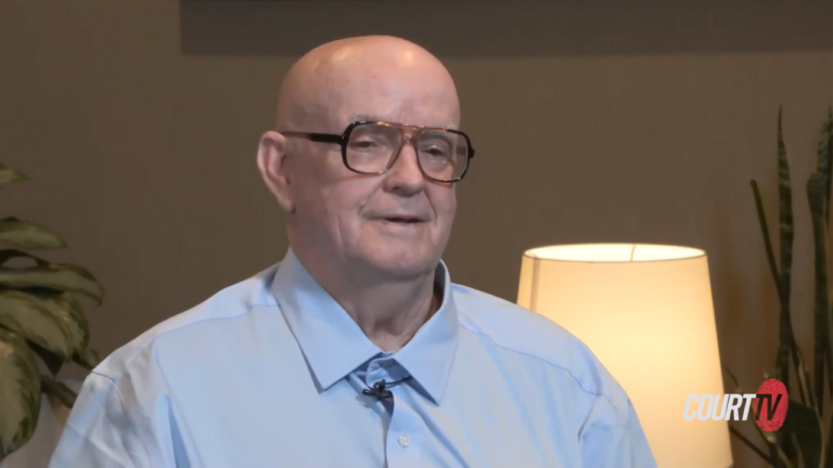 Michael Turney speaks to the camera, wearing a blue collared shirt