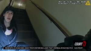 still frame from bodycamera video shows a woman sitting on a staircase