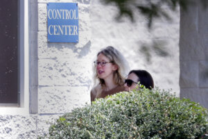 Elizabeth Holmes, left, is escorted by prison officials into a federal women’s prison camp