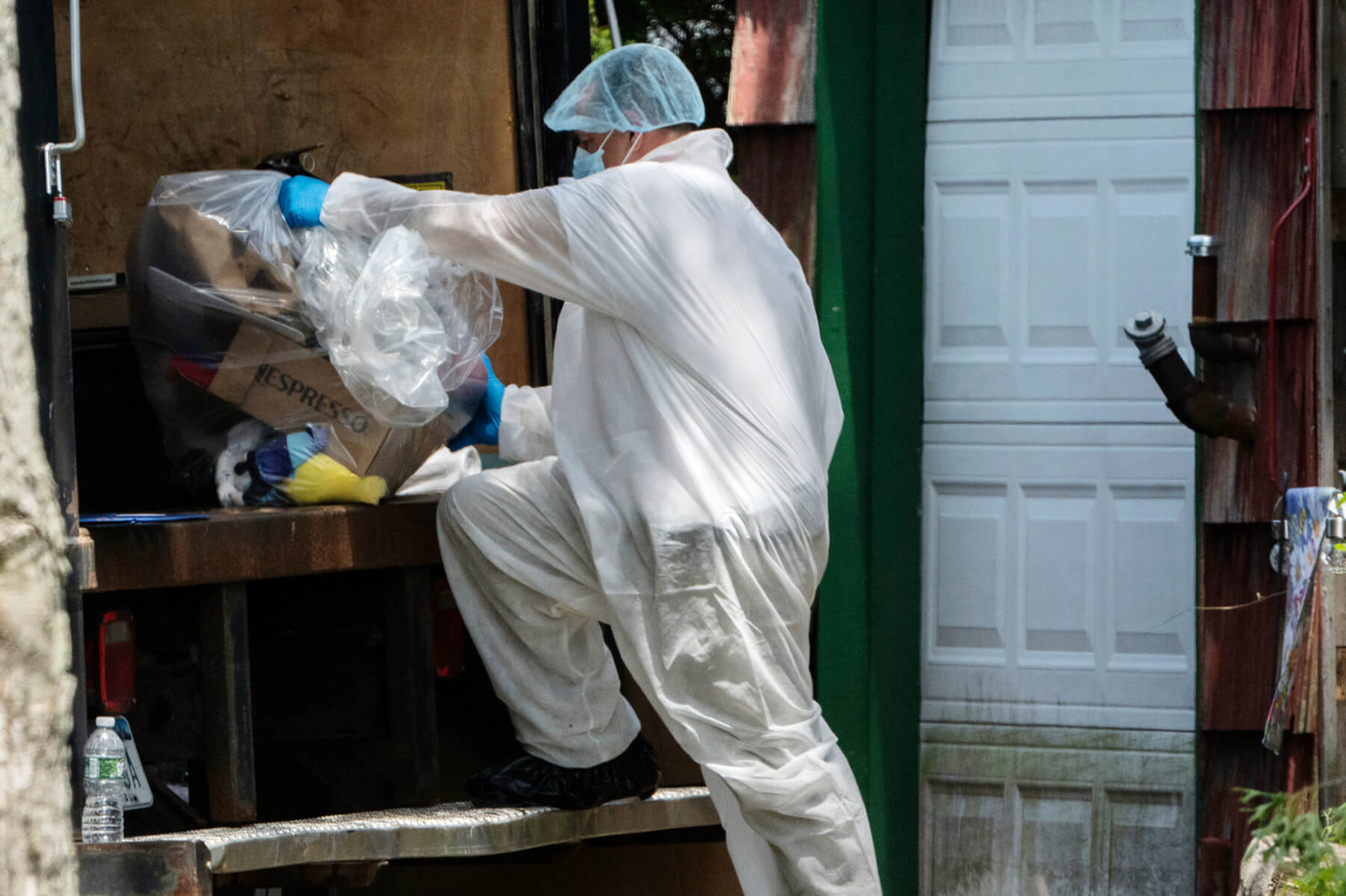 officer places a bag of items into the back of a truck