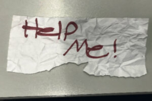 piece of paper says 'help me!' in red