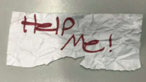 piece of paper says 'help me!' in red