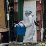 officers carry out a large item as law enforcement searches the home of Rex Heuermann