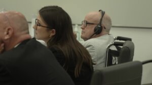 Michael Turney sits at the defense table wearing headphones