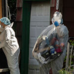 officers carry out a large item as law enforcement searches the home of Rex Heuermann