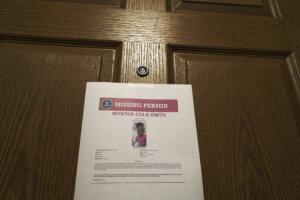 An alert poster featuring Wynter Smith is posted on a door.