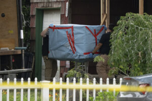 officers carry out a large item as law enforcement searches the home of Rex Heuermann