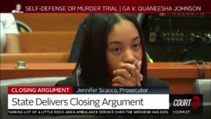 A woman sits in court with her hand over her face