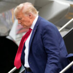 Donald Trump walks down the stairs of a plane