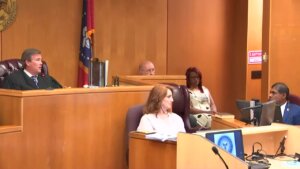 A judge presides over a courtroom as several people sit