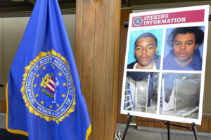 An FBI flag and a seeking information posterboard are set up next to a podium 