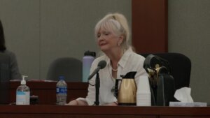 Woman speaks into a microphone while testifying in court.